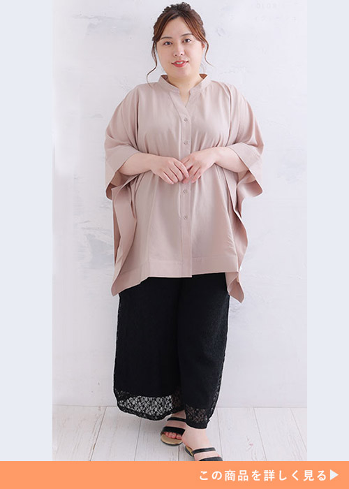 グレージュのポンチョシャツを着て、黒のレースパンツを履く女性