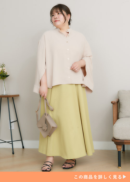 ライトベージュの袖スリットシャツを着て、イエローグリーンのマキシスカートを履く女性