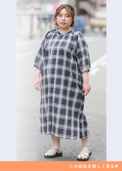 ネイビーのタータンチェック柄Aラインワンピースを着る女性。