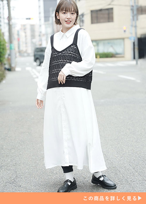 白のシャツワンピースに黒のレースビスチェを重ね着する女性