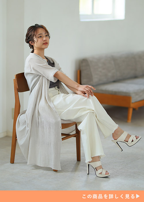 黒系トップス×白パンツに、ボタンを開けたライトベージュのシャツワンピースを羽織る女性