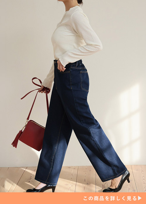 ストレートパンツ×白トップスに黒パンプスを履き、赤のバッグを持つ女性