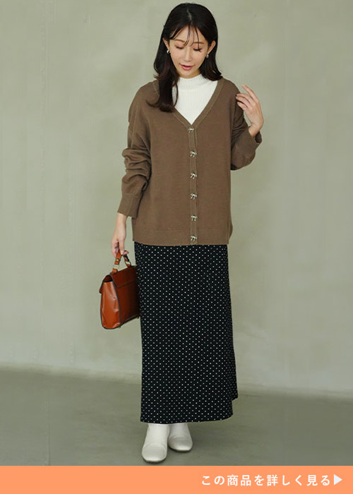 ドットのスカートにセミタートルニット、その上にモカカラーのカーディガンを羽織った女性