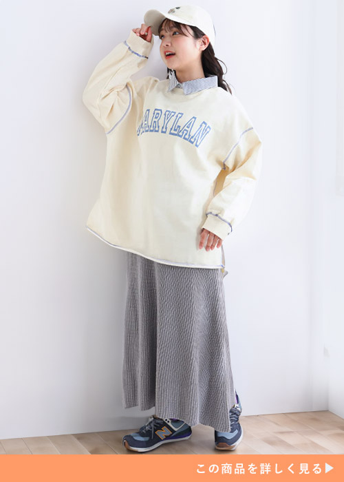 シャツ×オーバーサイズトレーナーを着て、グレーのニットAラインスカートを履く女性