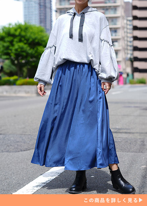 グレーのパーカ×ブルーのサテン地フレアスカートを着る女性