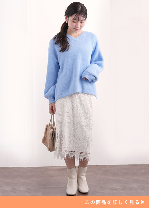 ライトブルーのVネックニット×白のレーススカートを着る女性