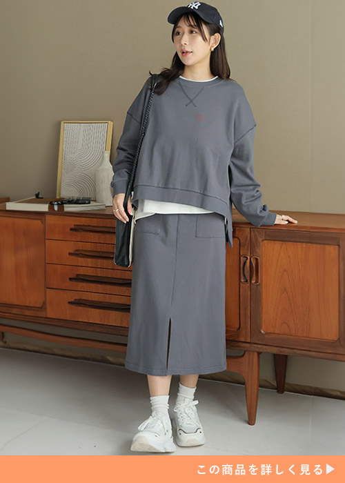 中に白Tをレイヤードして、チャコールのトップス×タイトスカートのセットアップを着る女性