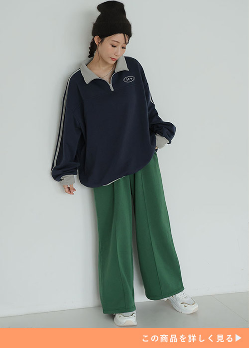 ネイビーのハーフジップトップス×グリーンワイドパンツを着る女性