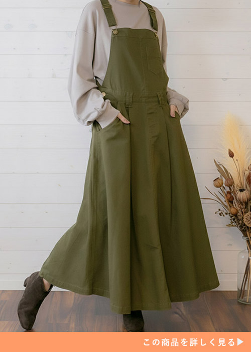 グレーのトップス×カーキのサロペットスカートを着る女性