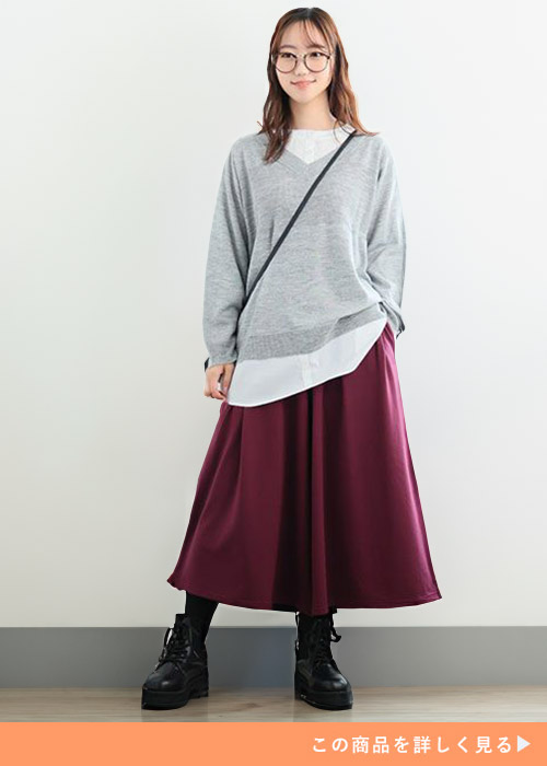 白のシャツにグレーのVネックニットを重ね着して、ワイン色のワイドパンツを履く女性