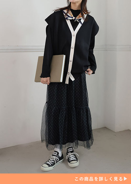 黒トップスとバイカラーベストを着て、ドットチュールスカートを履く女性