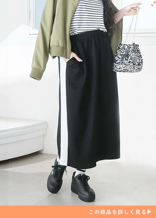 ボーダーT×ライン入りスカートにライトカーキのアウターを羽織る女性