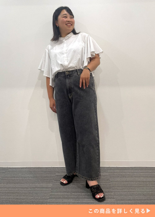 ブラックジーンズを履いて白のフリルシャツを着た女性