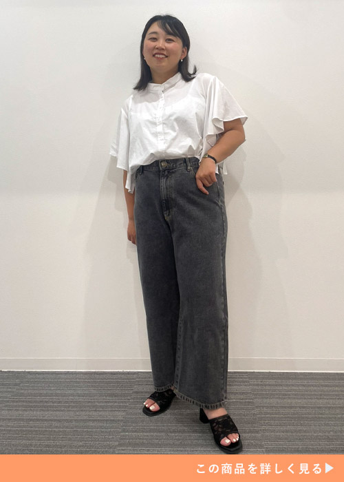 ブラックジーンズを履いて白のフリルシャツを着た女