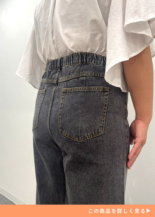 ブラックジーンズを履いて白のフリルシャツを着た女性の後ろ姿