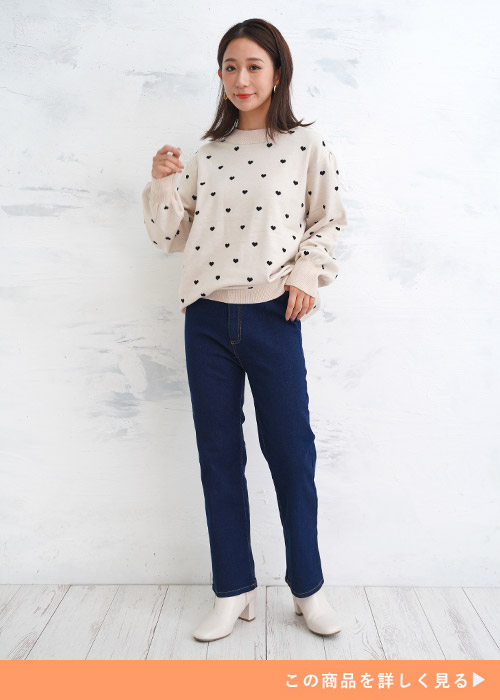 「ブルーのジーンズにハートドット柄の白トップスを着る女性