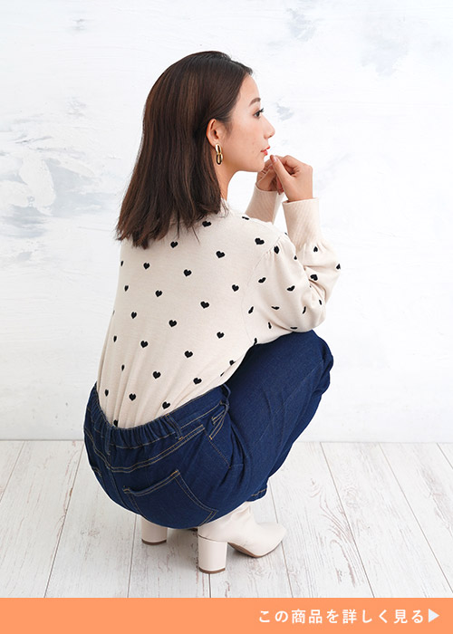 ブルーのジーンズにハートドット柄の白トップスを着てしゃがむ女性