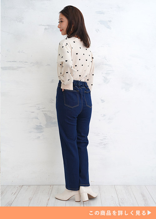 ブルーのジーンズにハートドット柄の白トップスを着て振り返る女性