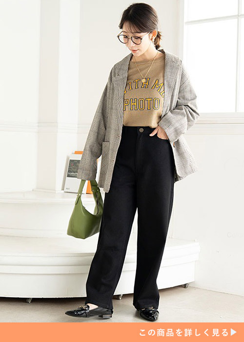 ブラックのワイドパンツとロゴトップスのコーデにジャケットを羽織る女性