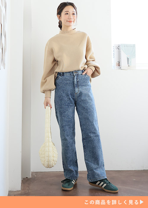 ネイビーケミカルのストレートパンツとベージュのハイネックニットのコーデにホワイトバッグを持つ女性