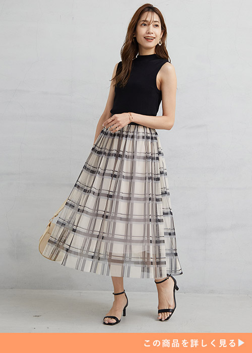 黒のノースリトップス×オフホワイトのチェック柄チュールスカートを着る女性