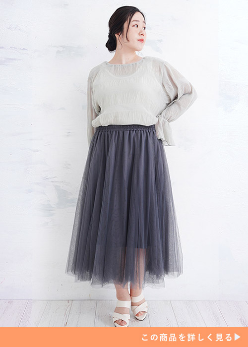 グレーのシアートップス×ダークグレーのチュールスカートを着る女性