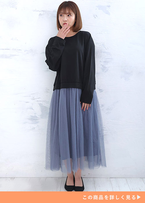 黒トップスとブルーグレーのチュールスカートをドッキングしたワンピースを着る女性