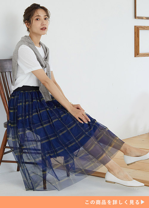 白Tにグレーのトップスを肩掛けし、青のチェック柄チュールスカートを履く女性