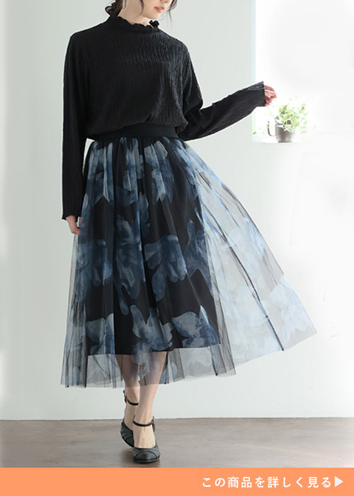 黒トップス×青の花柄チュールスカートを着る女性
