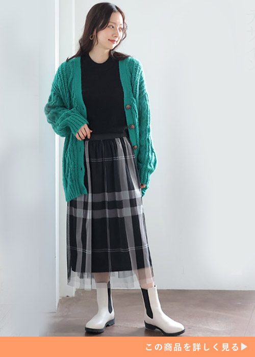 黒トップス×黒のチェック柄チュールワンピースにグリーンのカーディガンを羽織る女性