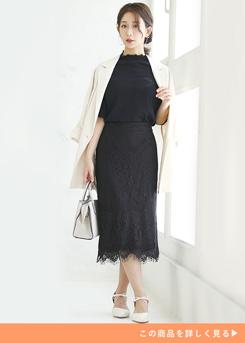黒トップス×黒レースのタイトスカートを着て、白のビッグジャケットを肩に羽織る女性