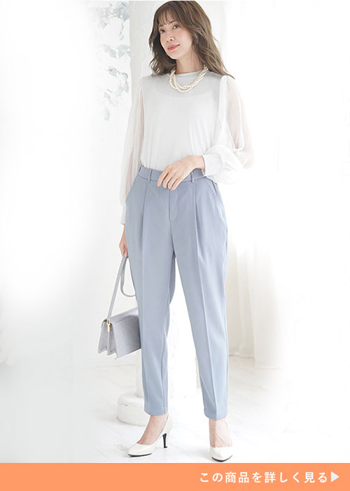 白のシアーブラウス×水色のテーパードパンツを着る女性