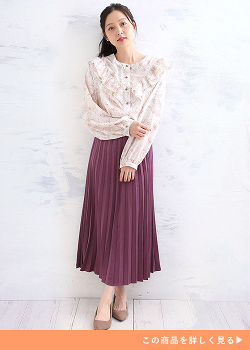 花柄のフリルブラウス×紫のプリーツスカートを着る女性
