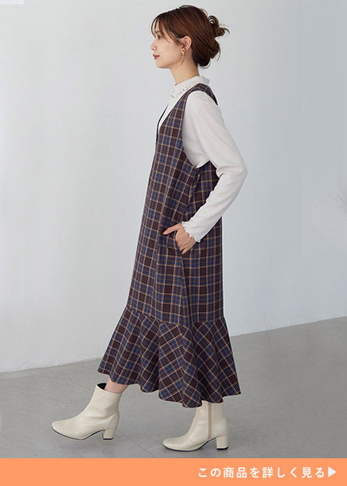 白のトップス×チェック柄のジャンスカを着る女性