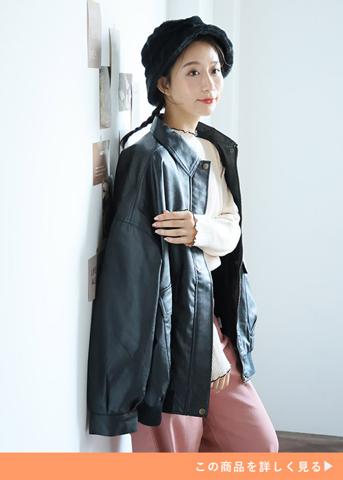 白トップス×くすみピンクのパンツにレザージャケットを肩掛けする女性