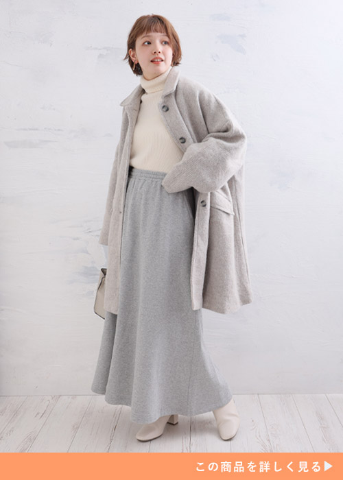 白のタートルネック×グレーのスウェットスカートにグレーのコートを羽織る女性