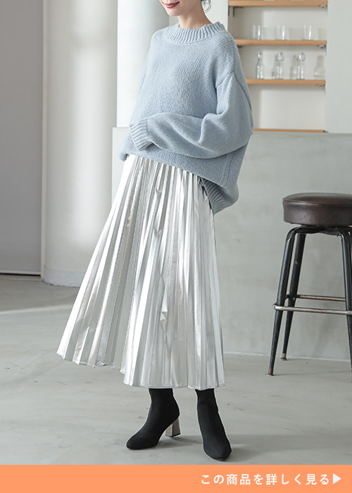 水色のニット×シルバーのプリーツスカートを着る女性