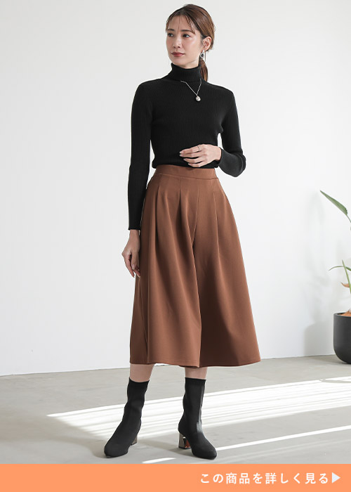 黒のタートルネックニット×茶のスカンツを着る女性