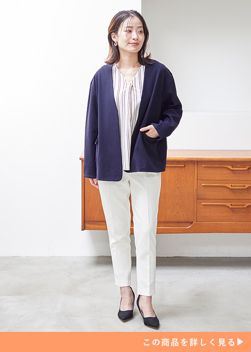 ストライプ柄ブラウス×白パンツに、ネイビーのノーカラージャケットを羽織る女性