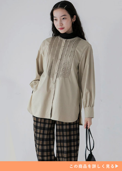 ベージュのピンタックブラウス×チェック柄パンツを着る女性