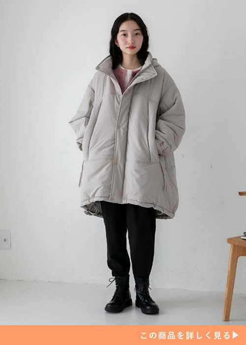 ベージュのオーバーサイズのロングコートにブラックパンツを履く女性