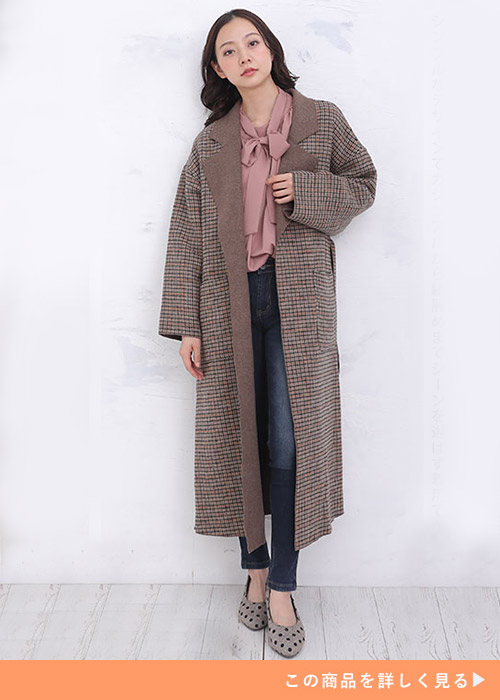 ブラウンチェックのチェスターオーバーコートにボウタイブラウスとデニムのコーデをする女性
