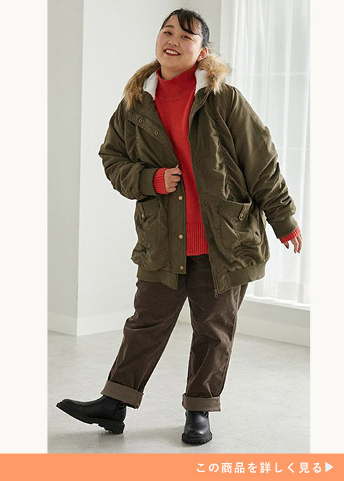 カーキの裏ボアモッズコートに同系色のカーキのパンツを合わせ、赤のニットを着る女性