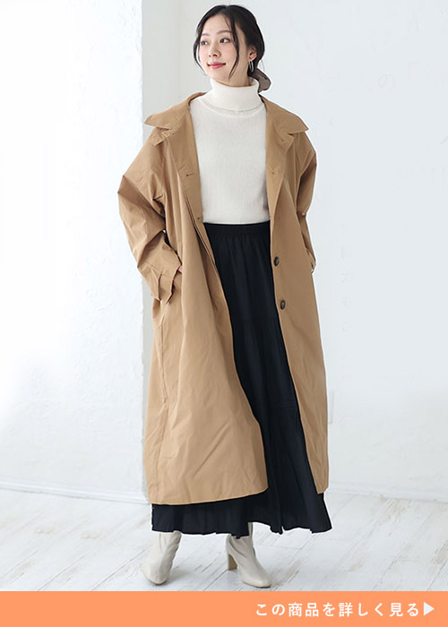 キャメルのナイロンカラースタンドワッシャーコートに白のタートルニットと黒スカートを合わせる女性