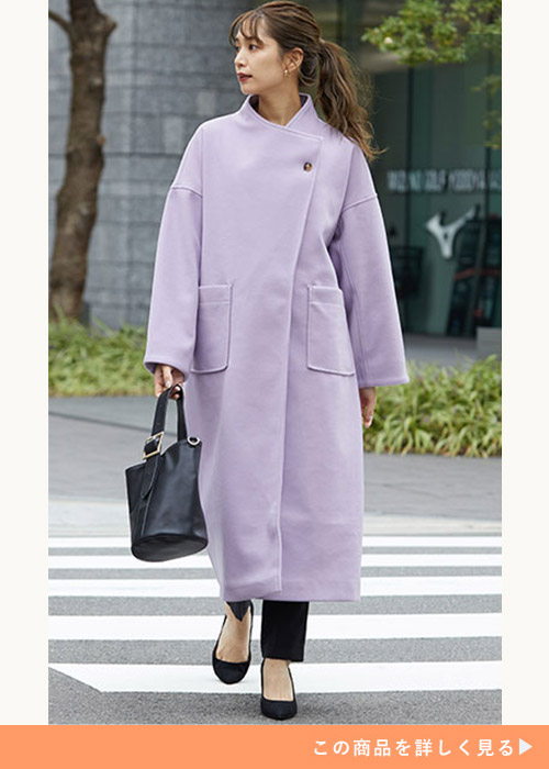 淡色紫のコートに黒のスキニーパンツとシューズ、バッグを合わせる女性