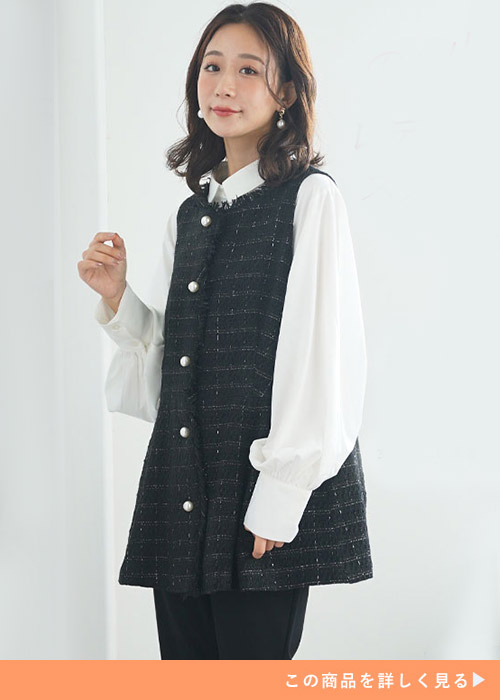 ホワイトのブラウスにブラックチェックのツイードペプラムベストを合わせる女性