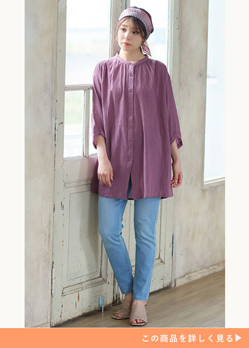 プラム色のブラウス×デニムを着る女性