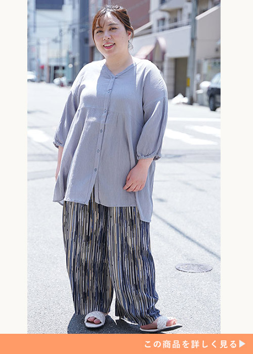 ライトグレーのブラウス×ブルー系の柄ワイドパンツを着る女性