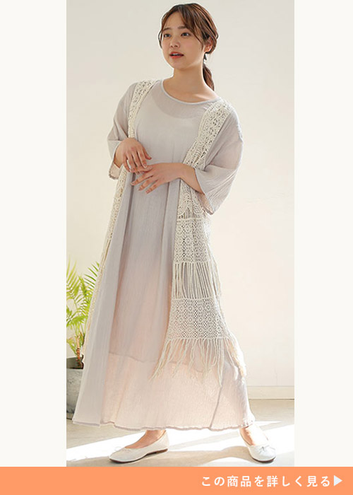 ライトベージュのシアーワンピを着て、白のレースジレを羽織る女性