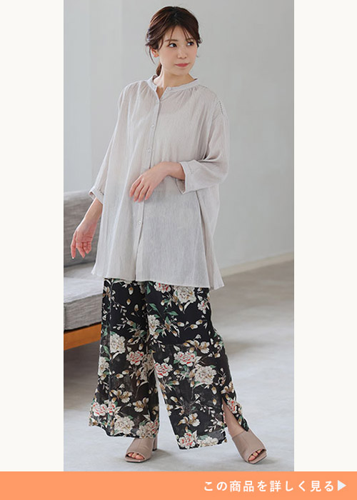 ベージュのシアーブラウス×黒の花柄ワイドパンツを着る女性